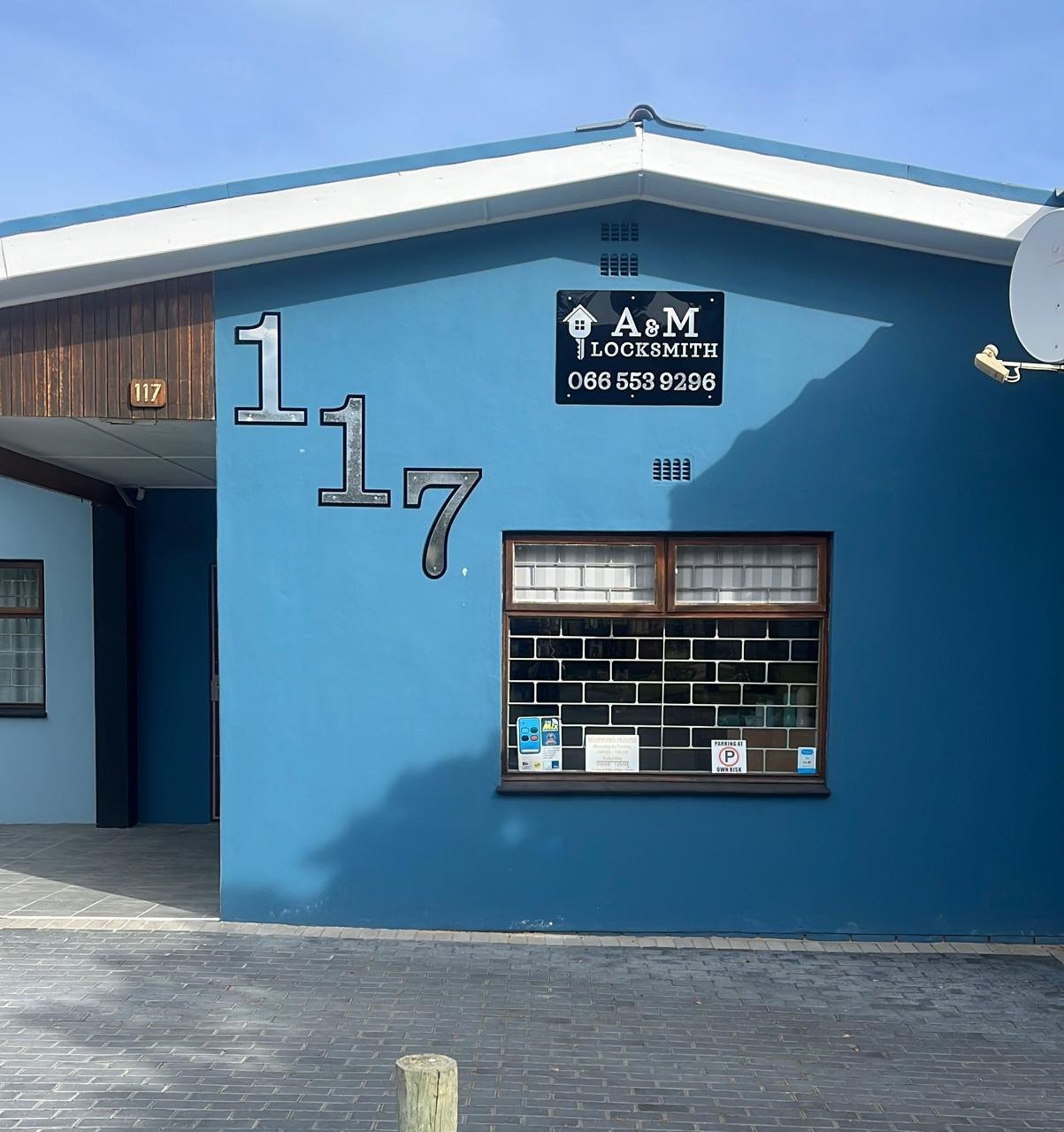 The blue A & M Locksmith shopfront with a large 117 on Main Road, Kleinmond