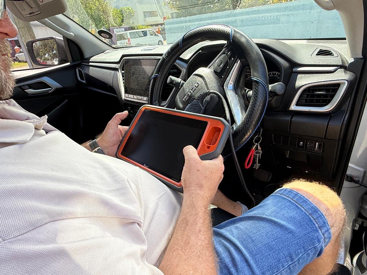 A key programming tablet plugged into the diagnostic port of an Isuzu bakkie