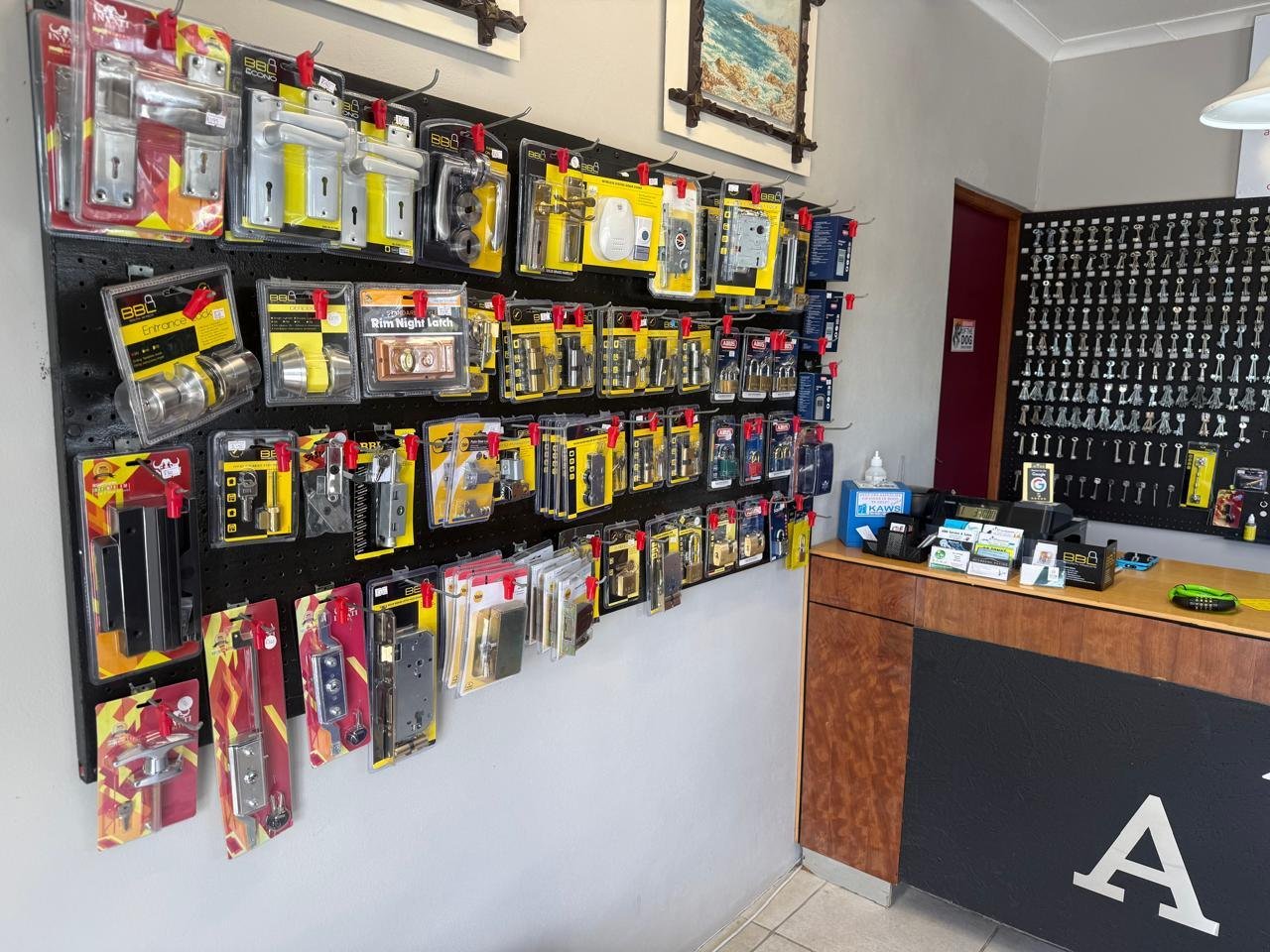 A pegboard wall of door handles, mortice locks, night latches and padlocks for sale at A & M Locksmith in Kleinmond